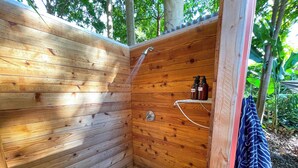 Une cabane en bois dotée d’une baignoire et d’une douche intégrées.