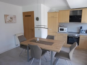 Et moderne køkken med træskabe, en mikroovn, ovn og spiseplads med bord og stole.