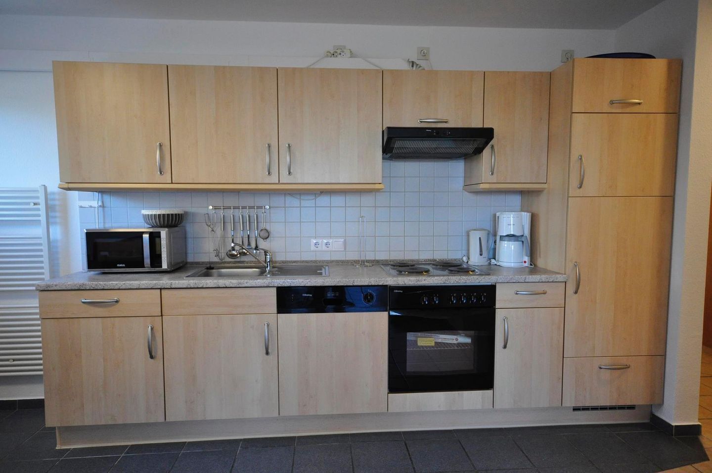 A modern kitchen with wooden cabinets, a microwave, a coffee maker, and a dishwasher.