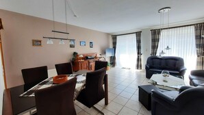 Una sala de estar moderna con comedor, que incluye un sofá, sillas, una mesa de centro y una mesa de comedor.