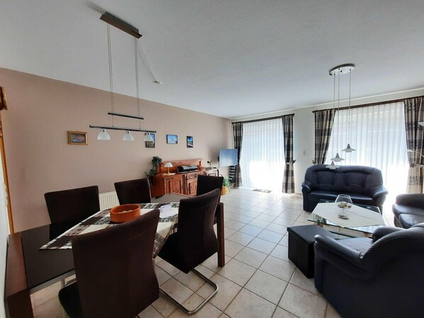 A modern living room with a dining area, featuring a sofa, chairs, a coffee table, and a dining table.