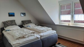 Un dormitorio con dos camas, una ventana con contraventanas y un radiador.