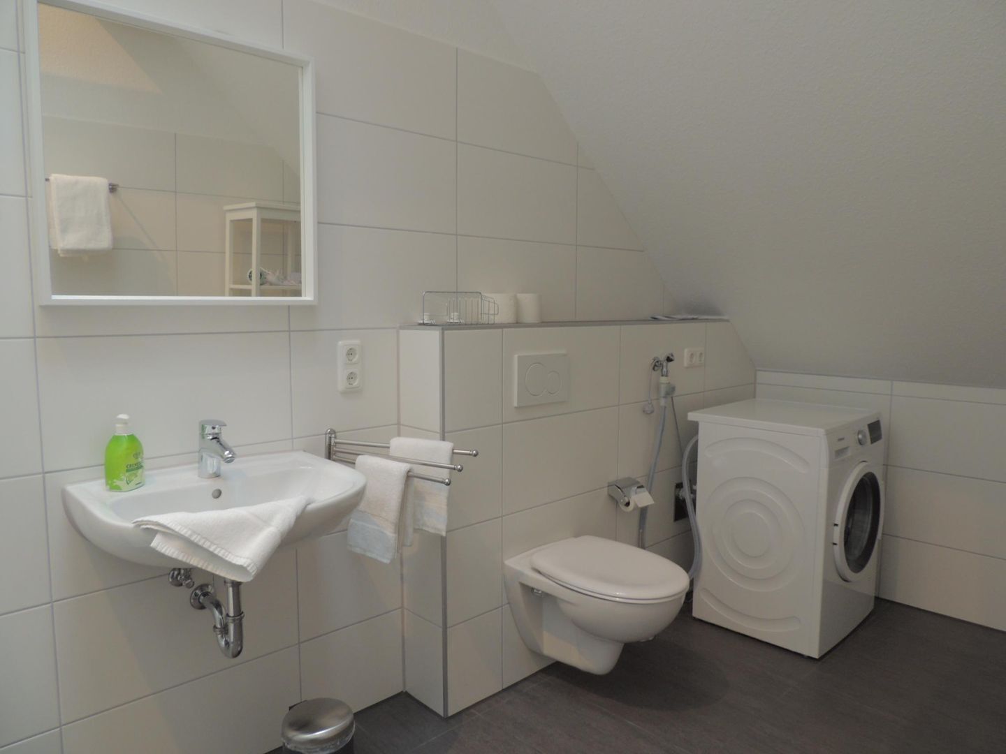 Een moderne badkamer met een wastafel, toilet en een wasmachine.