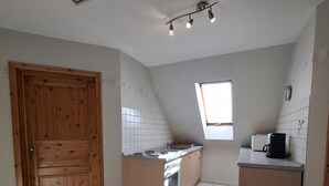 A kitchen with a wooden door, tiled floor, a window, and a small countertop with a coffee maker. - House Klabautermann - House Klabautermann Blockshausen 1 Apartment 2 (Neuharlingersiel)