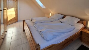 A bedroom with a sloped ceiling, a wooden bed, a nightstand, and a skylight. - House Klabautermann - House Klabautermann Blockshausen 1 Apartment 2 (Neuharlingersiel)