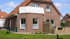 A two-story brick house with a sloped roof, white window shutters, and a wooden gate. - House Klabautermann - House Klabautermann Blockshausen 1 Apartment 2 (Neuharlingersiel)