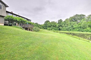 A house with a deck overlooking a pond and lush greenery.