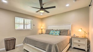 A bedroom with a bed, nightstand, ceiling fan, and window with blinds. - Tucson Getaway w/ Private Pool & Gas Grill! (Tucson)