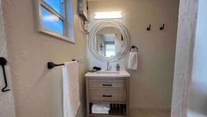 Een badkamer met een ronde spiegel, een wastafel en een handdoekhouder.