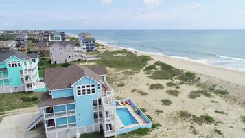 A coastal property with a large blue house featuring a swimming pool and multiple balconies.