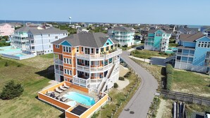 Een meerhoog woongebouw met een zwembad, balkons en uitzicht op de oceaan.