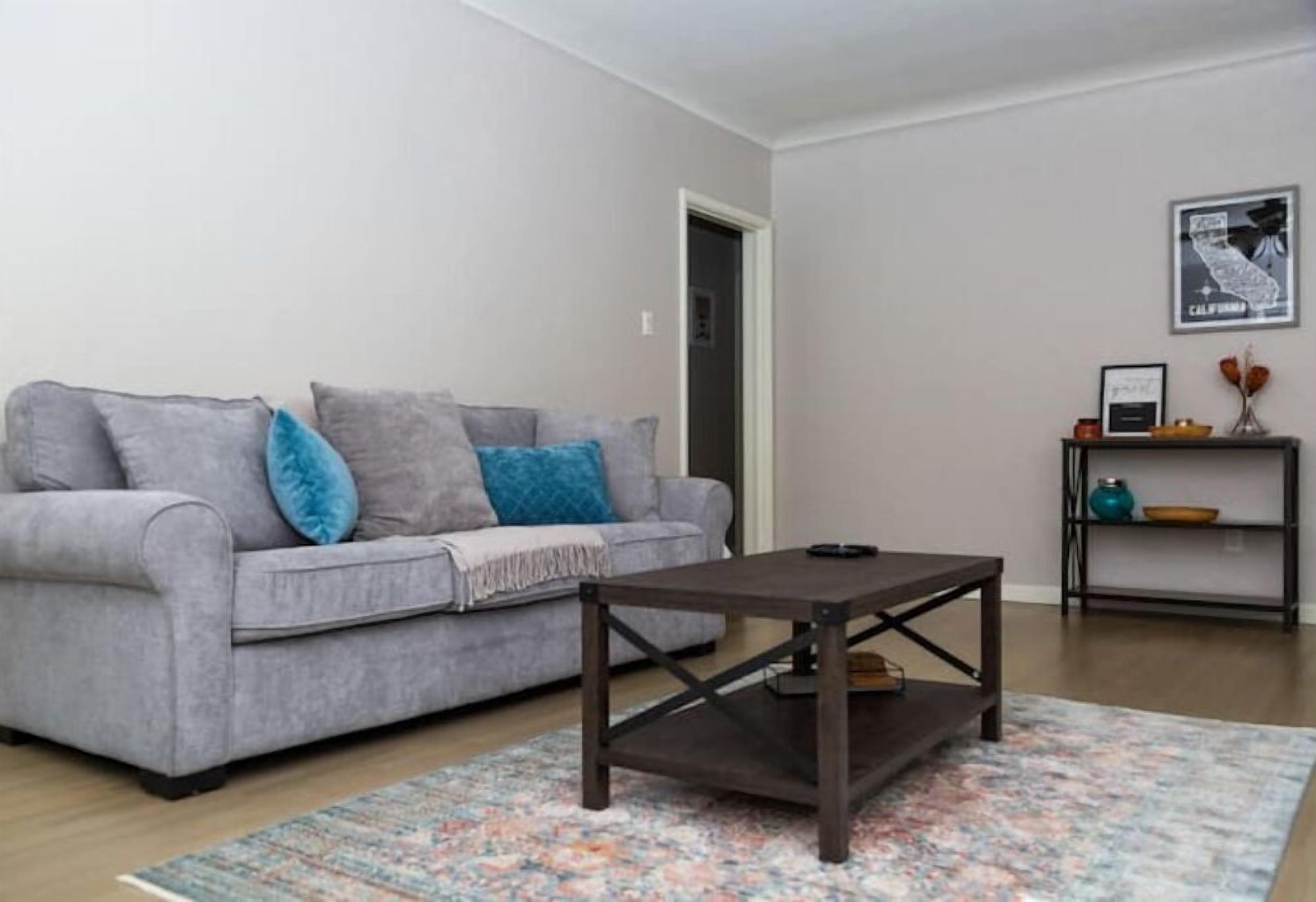 Un salon avec un canapé gris, une table basse en bois foncé et un tapis à motifs.