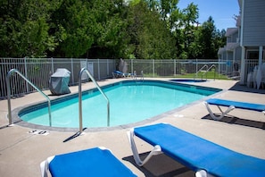 A swimming pool with a metal fence, lounge chairs, and a covered seating area. - Central Fish Creek - Hilltop Hideaway Condo (Fish Creek)