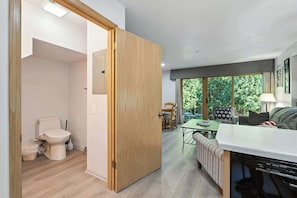 A modern kitchen with a dishwasher, a dining area with a table and chairs, and a view of the outdoors through large windows.