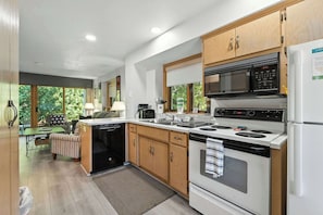 A modern kitchen with wooden cabinets, a built-in microwave, a stove, and a dishwasher.