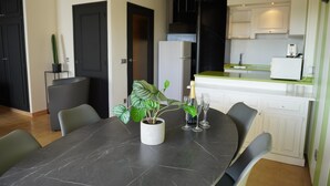 Une cuisine moderne avec des meubles blancs, un plan de travail noir et un coin repas comprenant une table et des chaises.