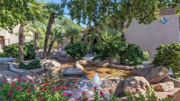 A landscaped garden with a small water feature, palm trees, and red flowers. - Bright, Updated, Quiet N Scottsdale Escape (Scottsdale)