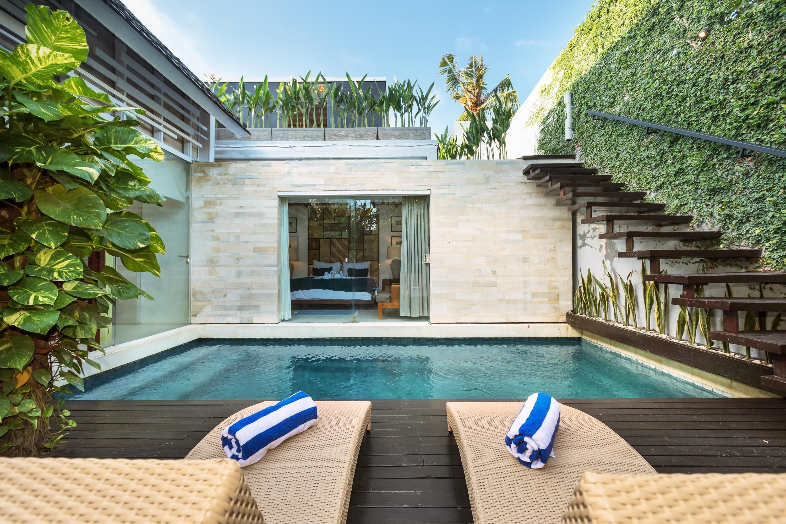 Ein moderner Poolbereich im Freien mit zwei Liegestühlen und einer Holzterrasse.