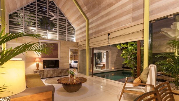 Amplo espaço interno com piscina, áreas de estar e televisão.