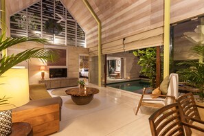 A spacious indoor area with a pool, seating arrangements, and a television. - Villa Yasa Canggu by Exotic Bali Properties (Canggu)