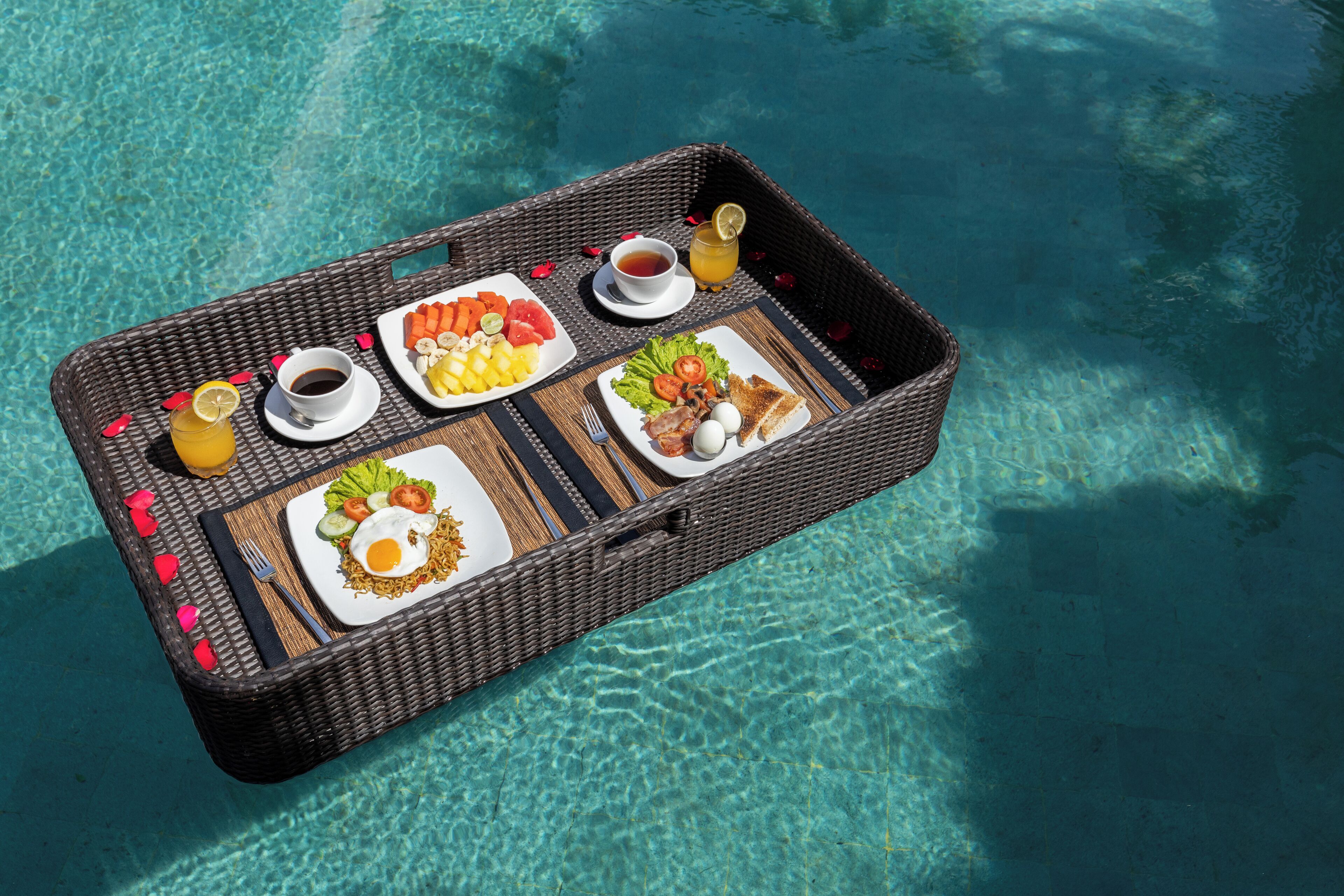A wicker tray with breakfast items by a pool.
