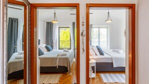 Ein Hotelzimmer mit zwei Betten, Holzboden und Blick auf einen Balkon.