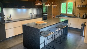 A modern kitchen with granite countertops, stainless steel appliances, and a central island with bar stools. - Beautiful 5-bed chalet in Les Carroz d'Araches (Les Carroz d'Araches)