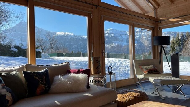 A cozy room with a large window, a sofa, a chair, and a small table. - Beautiful 5-bed chalet in Les Carroz d'Araches (Les Carroz d'Araches)