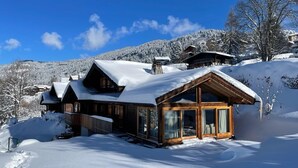A wooden cabin with large windows and a sloped roof, surrounded by snow-covered mountains. - Beautiful 5-bed chalet in Les Carroz d'Araches (Les Carroz d'Araches)