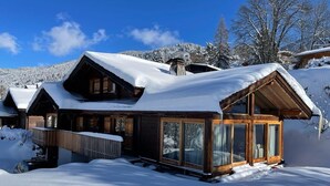 A wooden cabin with large windows and a snow-covered roof, surrounded by a snowy landscape. - Beautiful 5-bed chalet in Les Carroz d'Araches (Les Carroz d'Araches)
