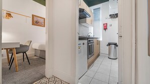 A compact kitchen with a refrigerator, oven, and sink. - Cosy Central Aberdeen 1 Bed Flat by Retail Park (Aberdeen)