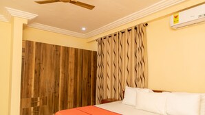 A bedroom with a bed, wooden wardrobe, curtains, and a ceiling fan.