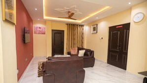 A living room with a brown leather sofa set, a ceiling fan, and a marble floor. - 2 Bed Furnished Apartment - Wifi, Aircon, Parking (Accra)