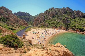 A beach with clear water, rocky cliffs, and a river. - Guinness B - Superior: Villa with Sea View Terrace and Pool Access (Costa Paradiso)