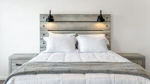 A bed with a wooden headboard, two bedside tables, and a grey blanket. - Comfortable 3 - Bedroom Norfolk Stay  – Minutes from Bases and ODU (Norfolk)