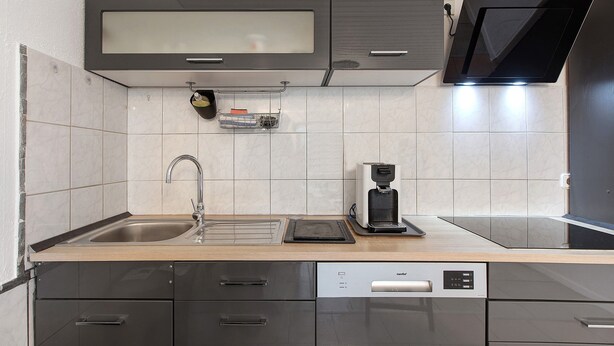 A modern kitchen with a built-in dishwasher, a coffee maker, and a microwave.