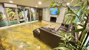 A spacious living area with a stone fireplace, a large sofa, and a view through a glass wall. - CLOSE TO DISNEYLAND & CONVENTION CENTER  (Anaheim)