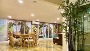 A dining area with a table and chairs, a large potted plant, and a mural with a coastal scene. - CLOSE TO DISNEYLAND & CONVENTION CENTER  (Anaheim)