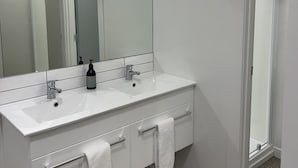 A modern bathroom with two sinks, a large mirror, and a door leading to another room. - Four bedrooms over looking queens gardens (Dunedin)