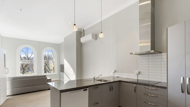 A modern kitchen with grey cabinets, a stainless steel sink, and pendant lighting. - Four bedrooms over looking queens gardens (Dunedin)