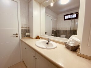 Une salle de bain avec un lavabo blanc, un miroir et un porte-serviettes.
