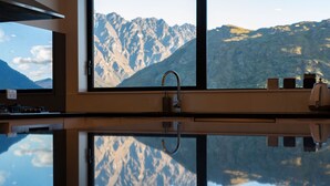 A kitchen with a reflective countertop, a sink, and a window with a mountain view.