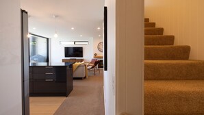 A modern living room with a TV, fireplace, and staircase.