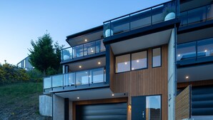 A modern multi-story house with a garage, large windows, and a balcony.