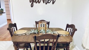 Una mesa de comedor servida con platos, vasos y una decoración central.