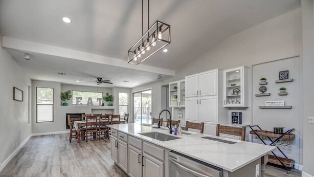 A modern kitchen with a central island, built-in cabinets, and a dining area with wooden chairs.