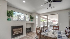 A modern dining area with a fireplace, a ceiling fan, and a view of the outside.