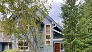 A rustic cabin with a steeply pitched roof, multiple windows, and a wooden door. - Upper Benchlands :Great townhouse, corner unit in quiet Treeline. Ski in/ ski out shuttle steps away (Whistler)