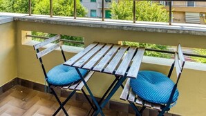 A balcony with a wooden table and two chairs, overlooking a residential area with multi-story buildings. - SAPIENZA Grand Apartment (ROMA)