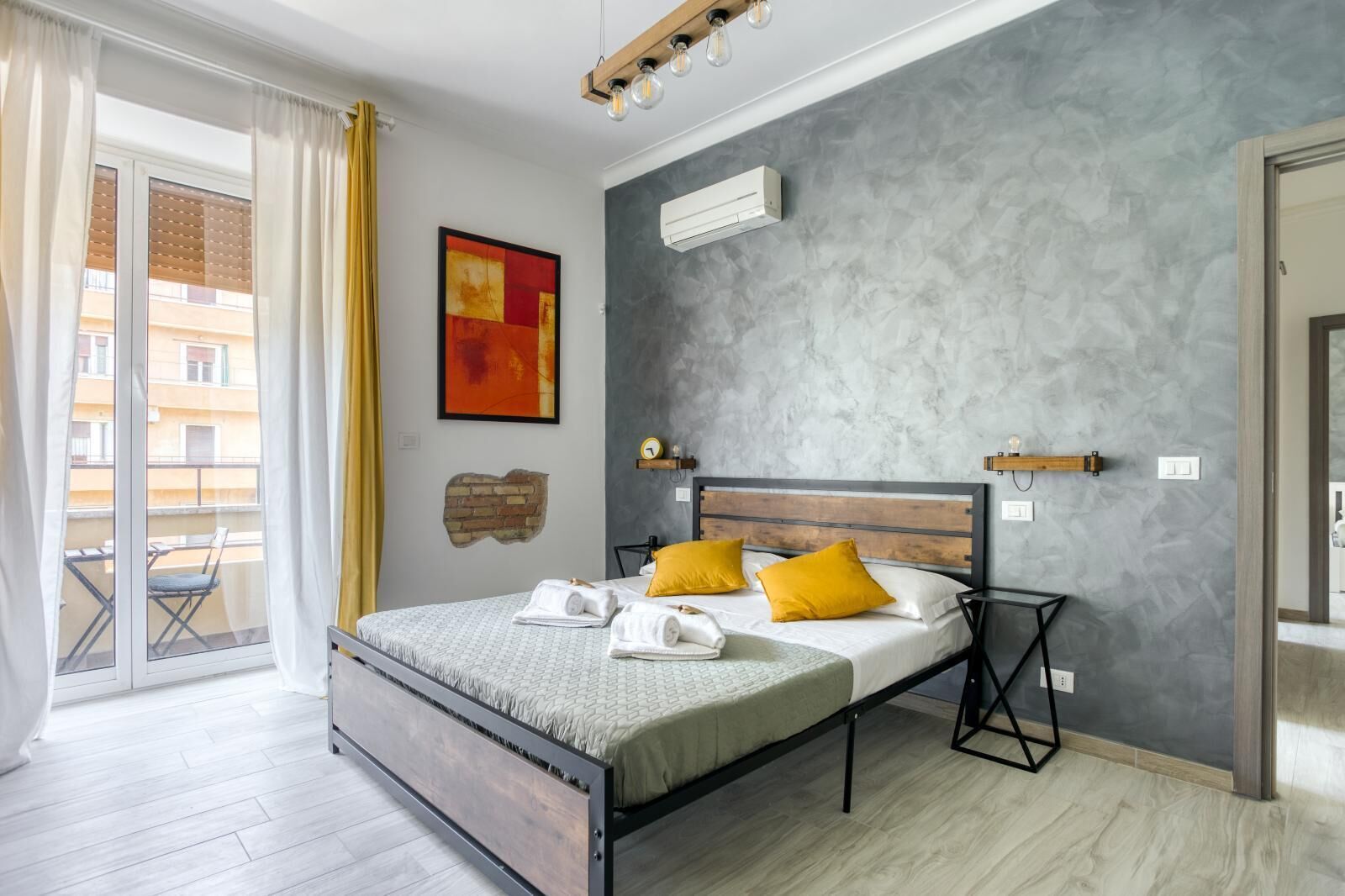 Een moderne slaapkamer met een bed, een wandairconditioner en uitzicht op het balkon.